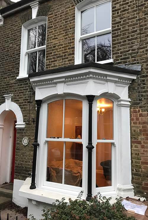 a white sash window on the ground floor seen from outside