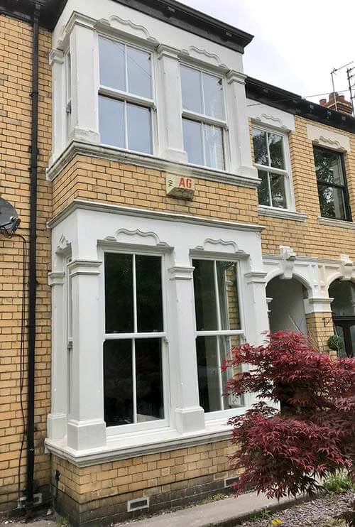two sliding sash windows fitted in a two storey house with beige brick
